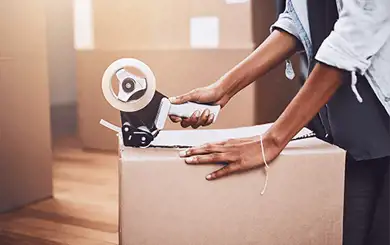 Image of person using packing tape to seal a moving box
