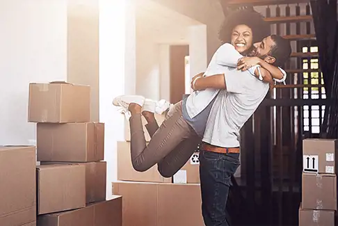 Image of happy man and woman hugging in front of packed storage boxes