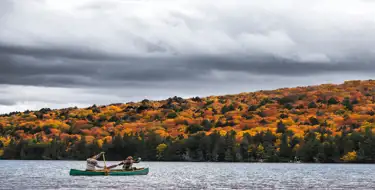 Image of canoe on lake with colorful trees surrounding