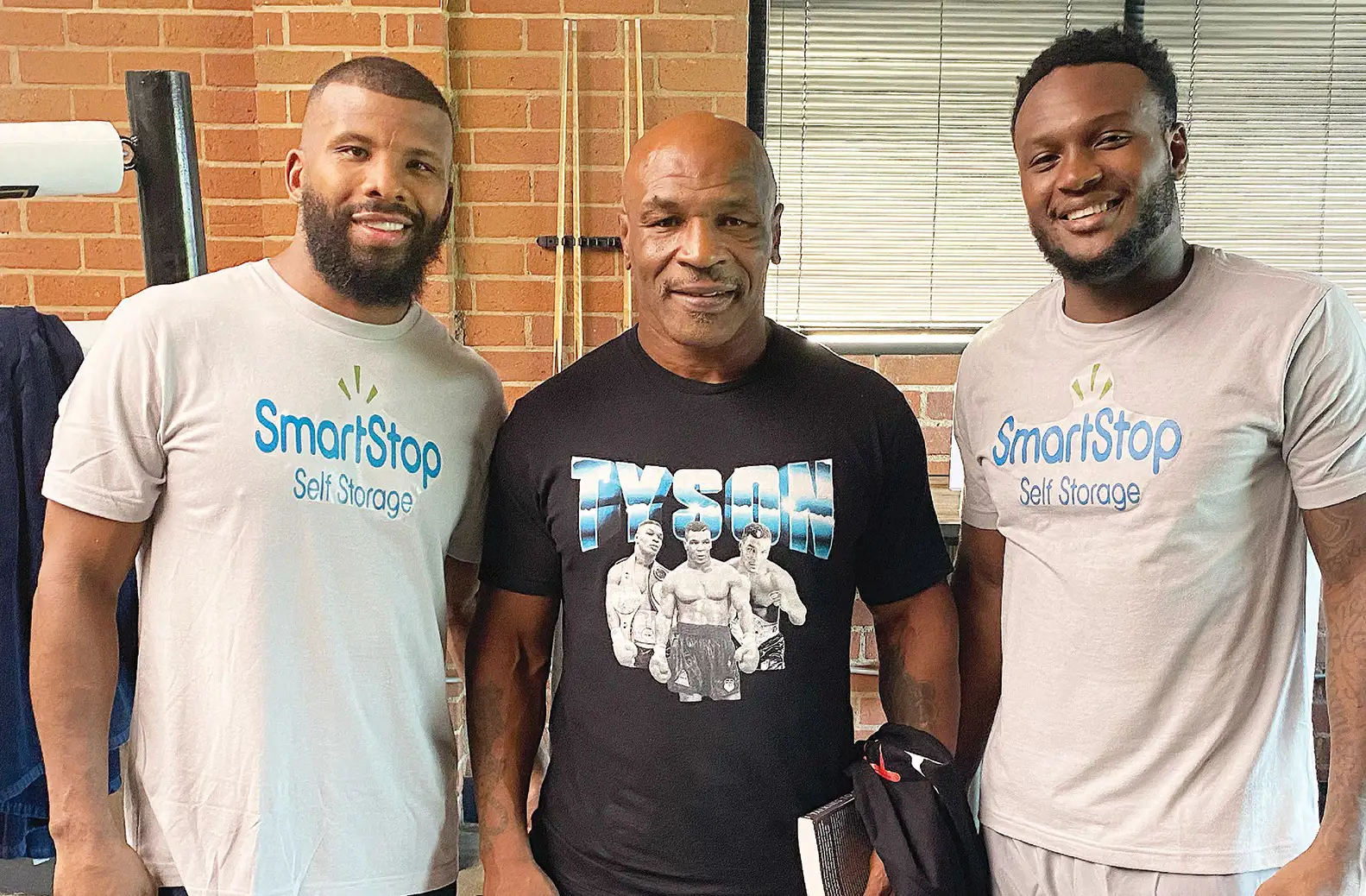 Mike Tyson posing with 2 boxers who are all set to fight at an event