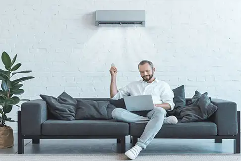 Image of a man sitting on a couch with a laptop computer
