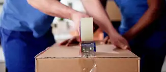 two movers taping cardboard box shut