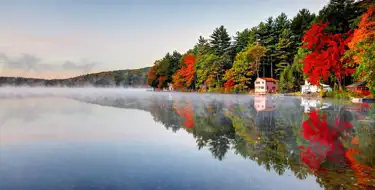 Image of clear lake surrounded by trees in autumn time
