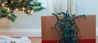 cardboard box with string lights spilling out over top next to christmas tree